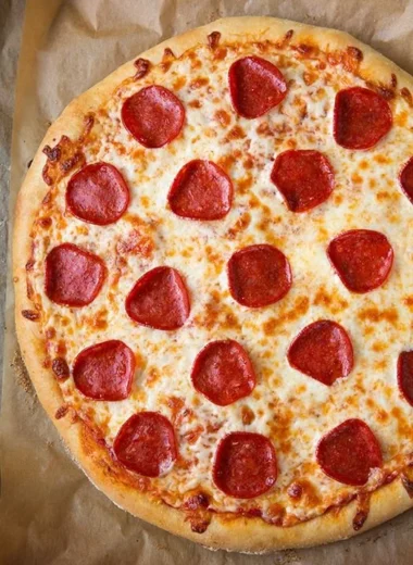 Delicious slice of pepperoni pizza topped with melted cheese and spices