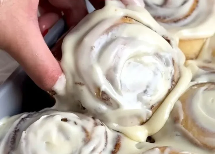 Freshly baked homemade cinnamon rolls topped with creamy icing
