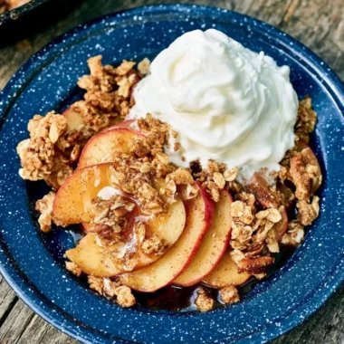 Vegan Campfire Apple Crisp served in a cast iron skillet by a campfire