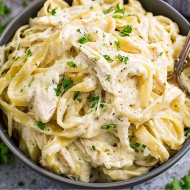 Creamy Instant Pot Chicken Alfredo served with pasta on a wooden table