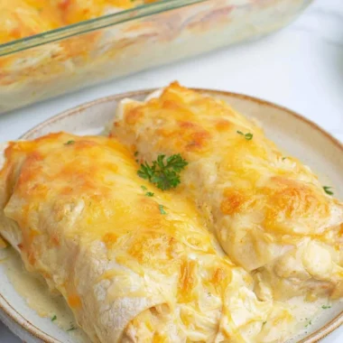 Creamy white chicken enchiladas topped with cheese and fresh herbs