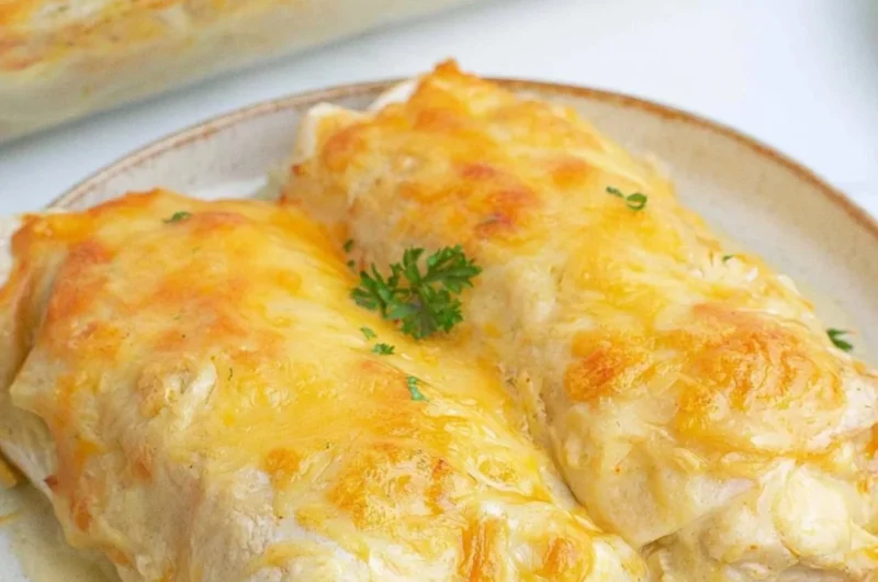 Creamy white chicken enchiladas topped with cheese and fresh herbs