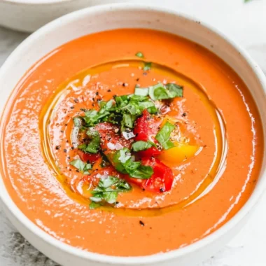 Bowl of vibrant vegan gazpacho garnished with fresh herbs and vegetables