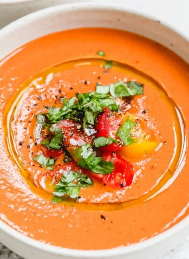 Bowl of vibrant vegan gazpacho garnished with fresh herbs and vegetables