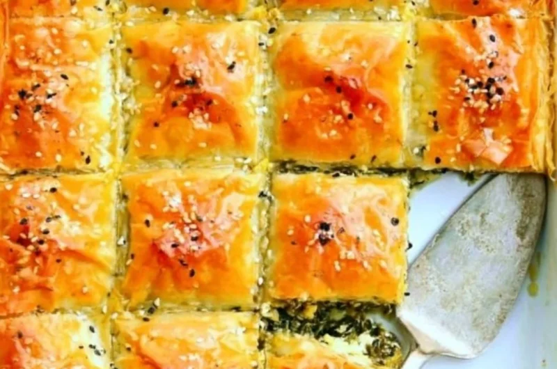 A freshly baked easy spinach pie on a wooden table, garnished with herbs.