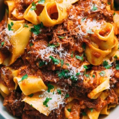 Bowl of homemade short rib ragu topped with herbs and served with pasta