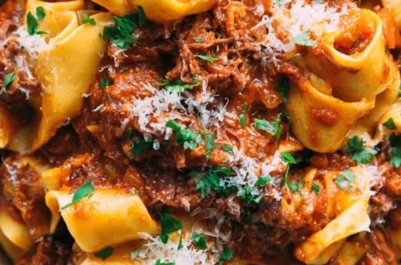 Bowl of homemade short rib ragu topped with herbs and served with pasta