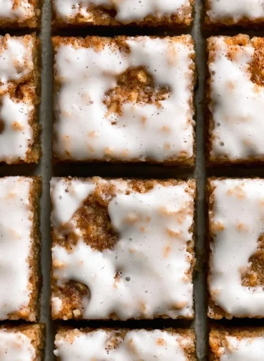 Delicious iced oatmeal cookie bars topped with creamy glaze on a plate.