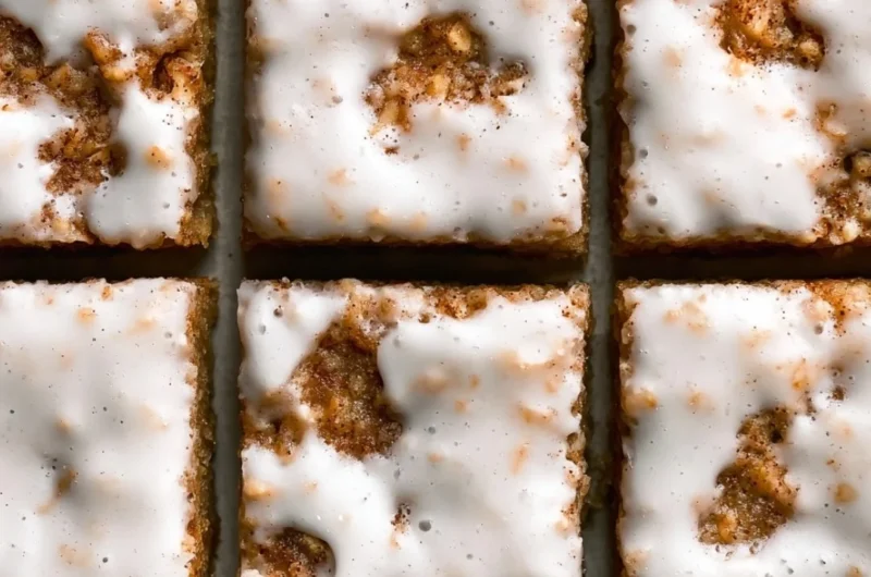 Delicious iced oatmeal cookie bars topped with creamy glaze on a plate.