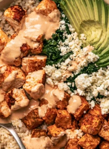 Healthy roasted chicken and sweet potato rice bowl garnished with greens