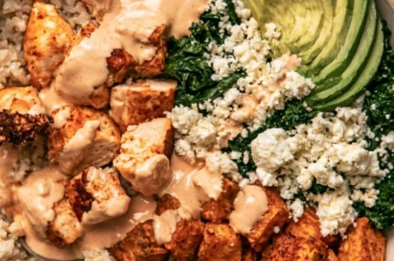 Healthy roasted chicken and sweet potato rice bowl garnished with greens