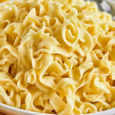 A delicious bowl of creamy cafeteria noodles topped with herbs and spices.