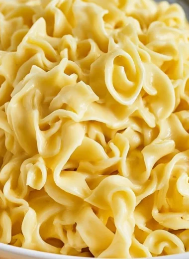 A delicious bowl of creamy cafeteria noodles topped with herbs and spices.