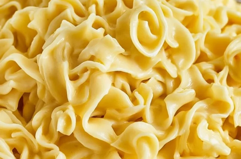 A delicious bowl of creamy cafeteria noodles topped with herbs and spices.